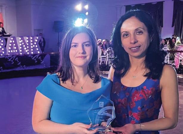 Danielle (Executive Lead C‐19 Network) and Sumeet (Deployment Coordinator IPC Health bicultural workforce) face the camera, holding the glass Inclusive Brimbank Award at the We Are Brimbank Awards ceremony.