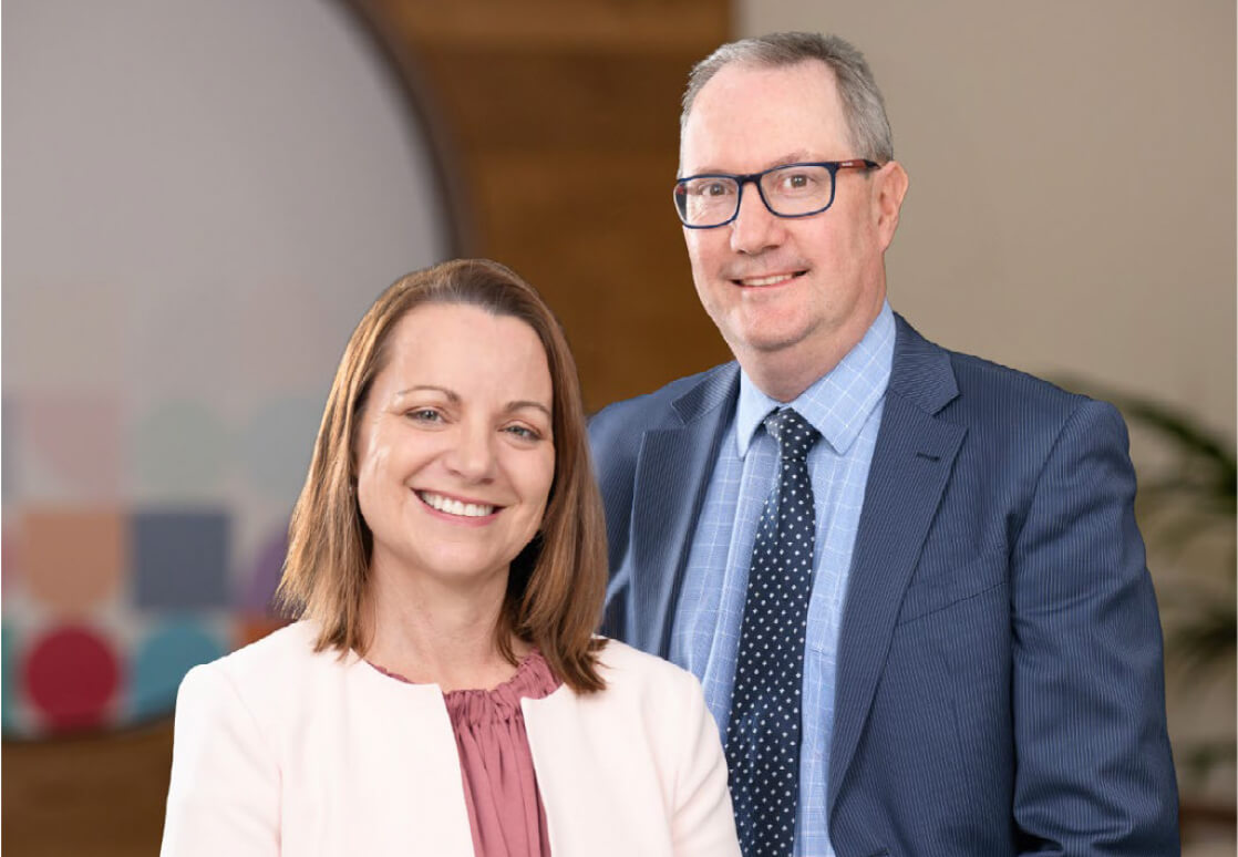 [GS1]: Jayne Nelson (IPC Health CEO) and Daryl Whitfort (IPC Health Board Chair) stand smiling in the lobby of the IPC Health Sunshine campus.