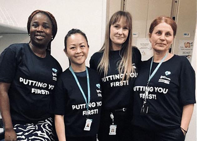 Four Client Services team members stand smiling together wear dark blue tshirts that say Putting you first.