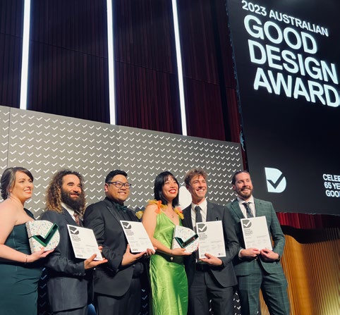 Elise De Losa (IPC Health Team Lead, Innovation and Design) on stage with five people from No Moss Co accepting the Digital Design and Social Impact awards for the Chop Out Convos app at the 2023 Australian Good Design Awards.