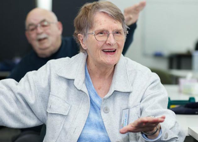 older woman and older man in background moving arms during binGO MOVE session