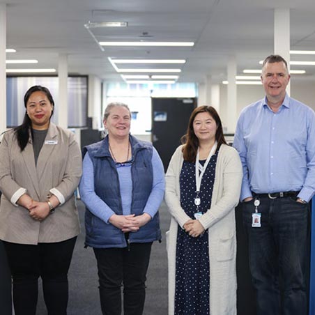 Four members of the IPC Health Care Finder Service team stand together in an open plan office,
smiling.